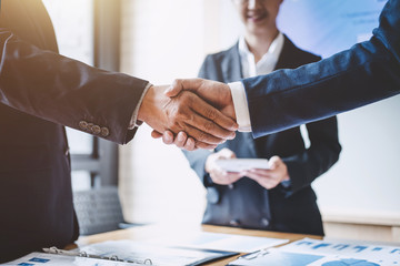 two men shaking hands while another guy watches