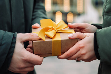 woman and man's hands holding gift between them