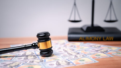 The gavel on a dollar bill in a courtroom represents the complex interplay between alimony law, alimony taxes, financial power, highlighting the need for clear legal frameworks, ethical considerations